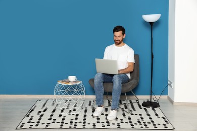 Man with laptop in stylish room interior, space for text