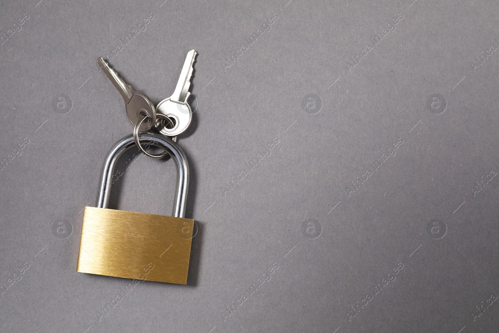 Photo of Steel padlock with keys on grey background, top view. Space for text