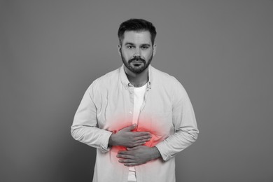 Image of Man suffering from abdominal pain on grey background. Black and white effect with red accent