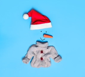 Photo of Creative snowman shape made of Santa hat and different items on light blue background, flat lay