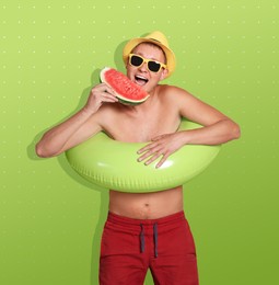 Image of Shirtless man with inflatable ring eating watermelon on color background. Summer season