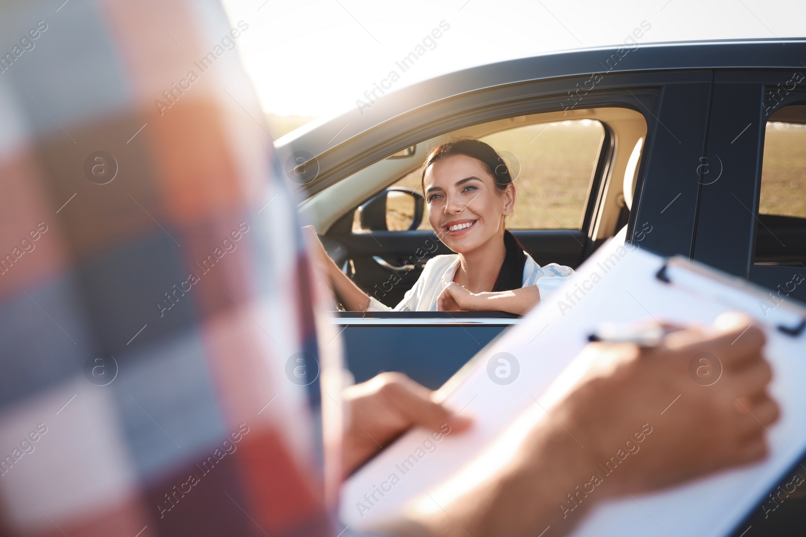 Photo of Young woman in car near her instructor outdoors. Driving school