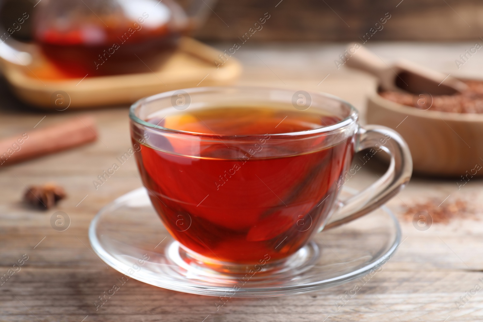 Photo of Freshly brewed rooibos tea on wooden table, closeup