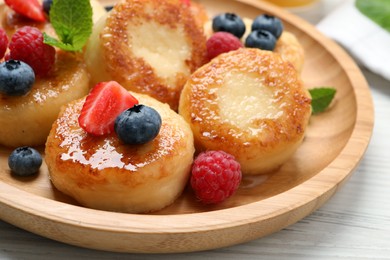 Delicious cottage cheese pancakes with fresh berries and honey on white wooden table, closeup