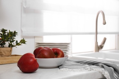 Photo of Bowl with ripe apples on counter in kitchen