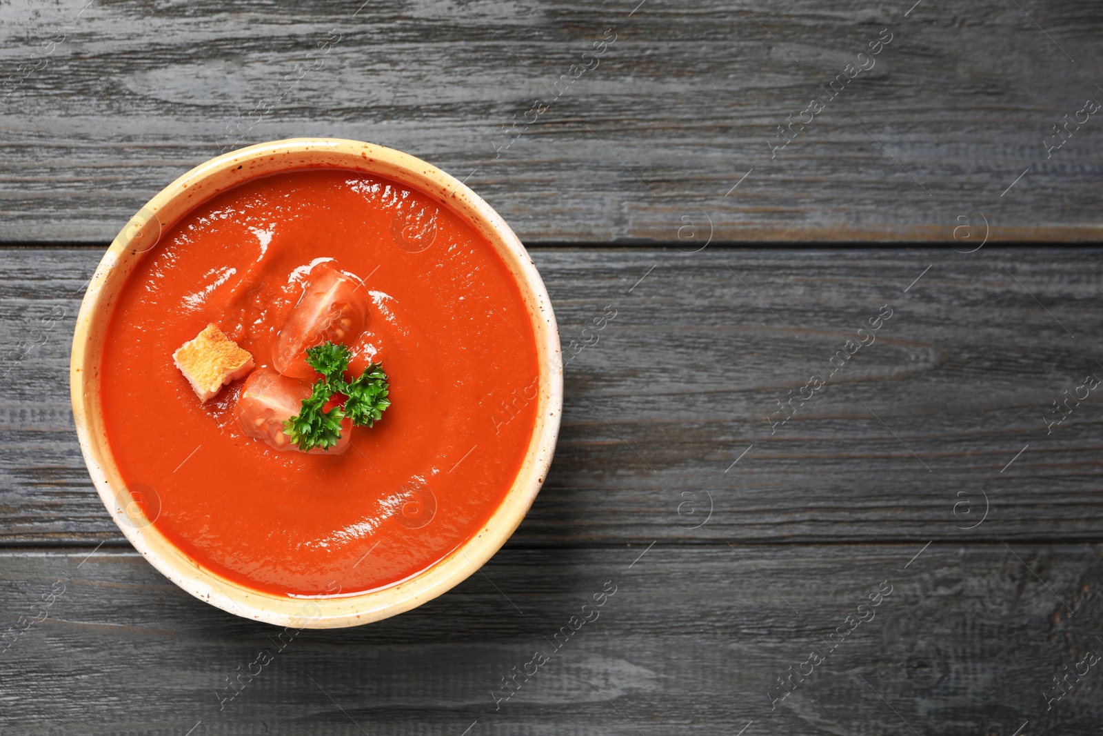 Photo of Bowl with fresh homemade tomato soup and space for text on wooden background, top view