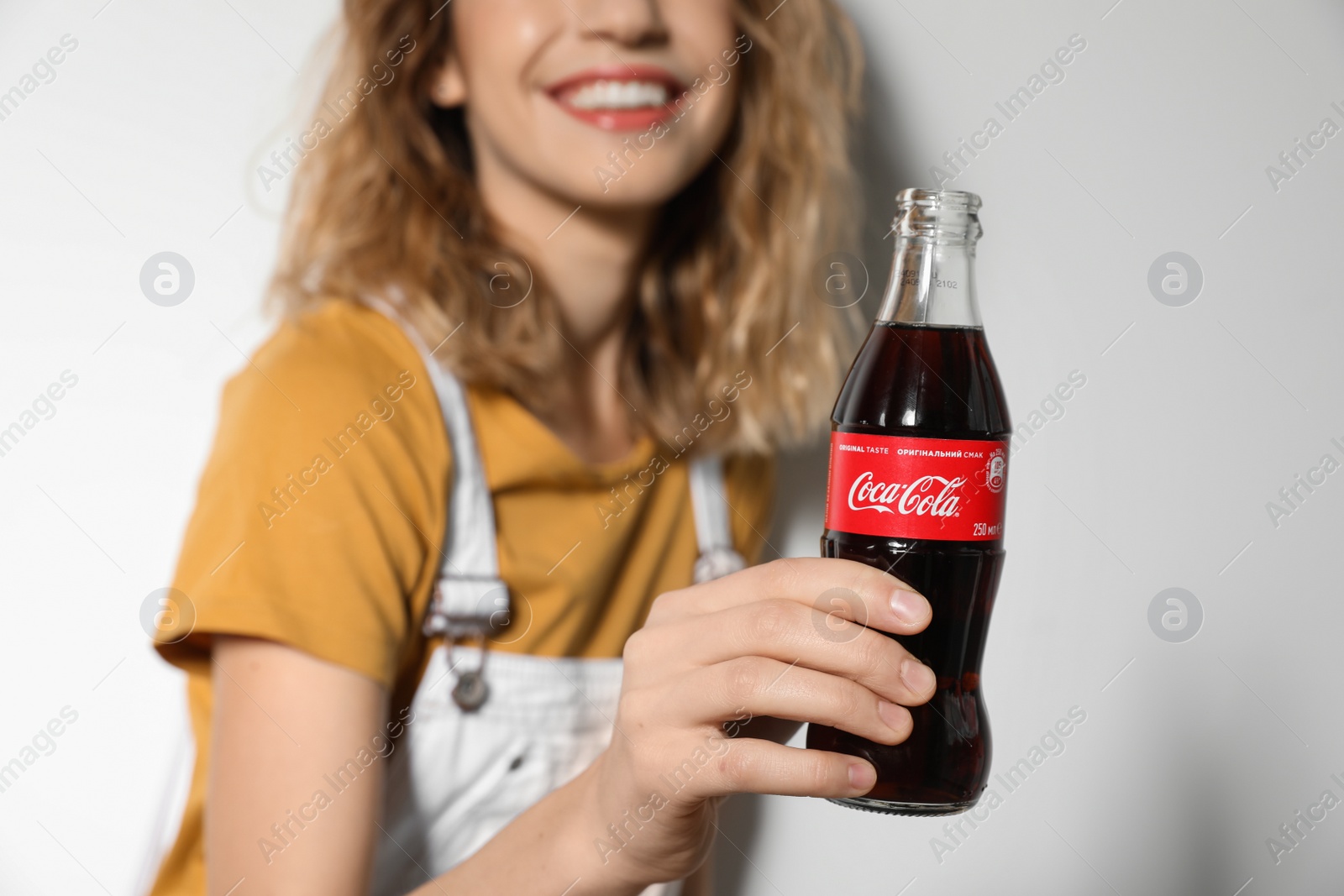 Photo of MYKOLAIV, UKRAINE - NOVEMBER 28, 2018: Young woman with bottle of Coca-Cola on white background, closeup