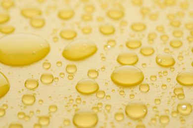 Photo of Water drops on yellow background, closeup view