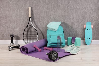Many different sports equipment near grey wall indoors