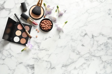 Photo of Many different makeup products and spring flowers on marble background, flat lay. Space for text