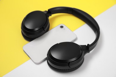 Photo of Modern wireless headphones and smartphone on color background