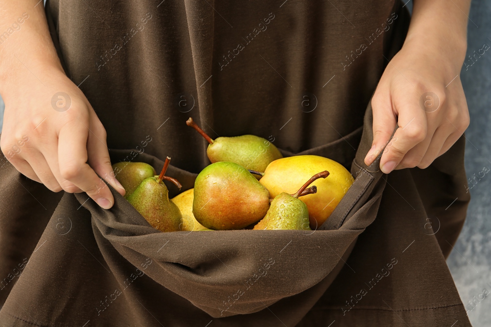 Photo of Woman in apron with ripe pears, closeup