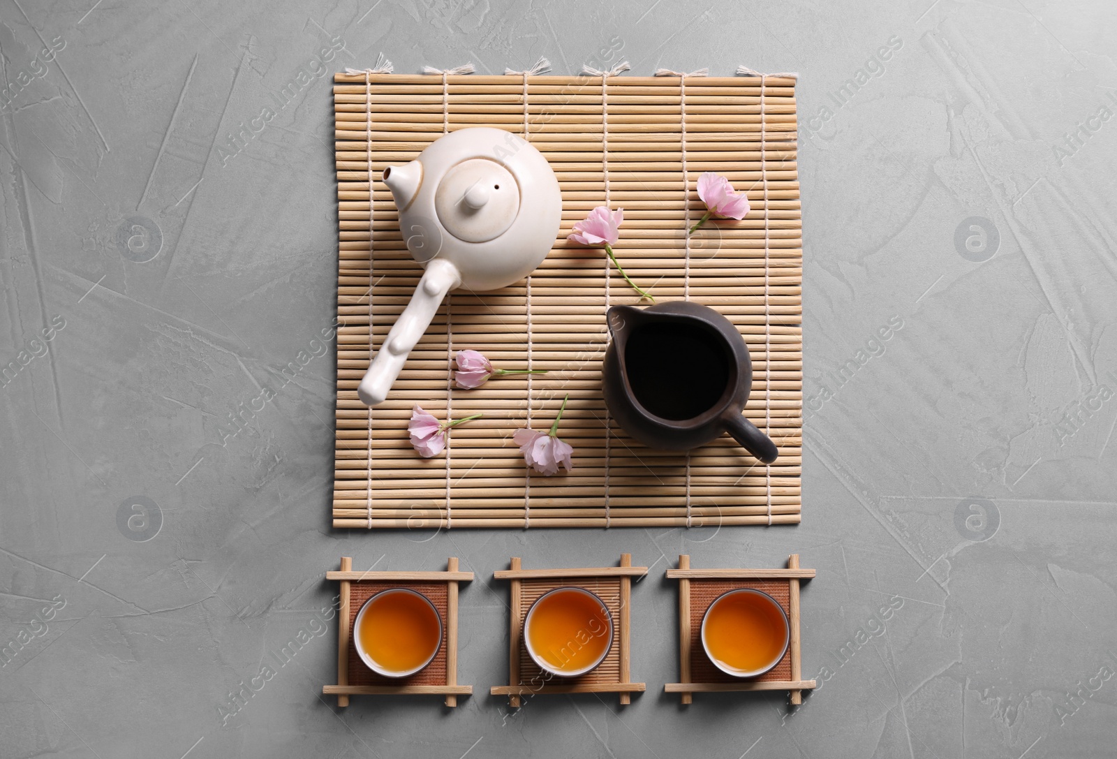 Photo of Beautiful set for traditional tea ceremony and sakura flowers on light grey table, flat lay