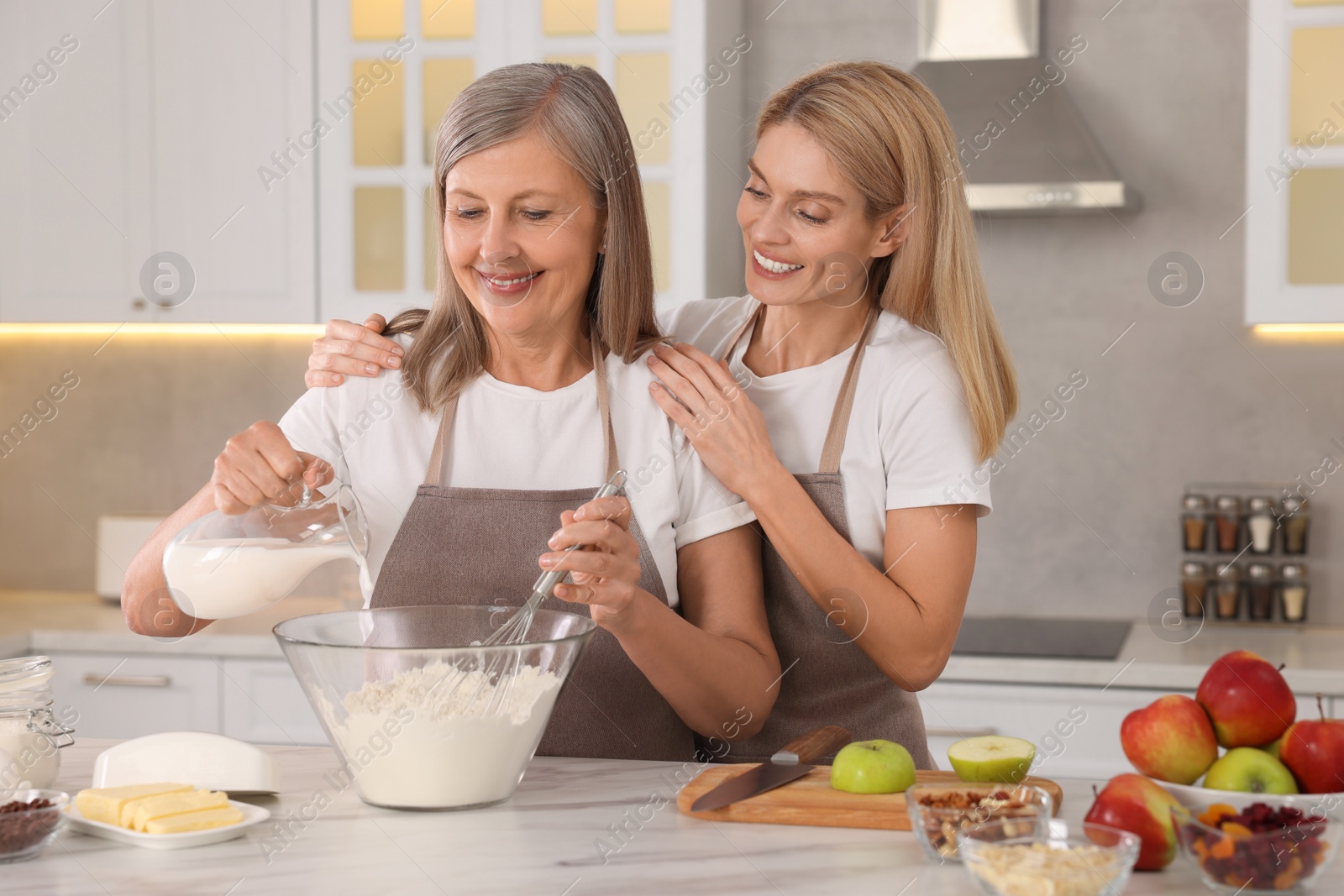 Photo of Happy mature mother and her daughter cooking together at kitchen