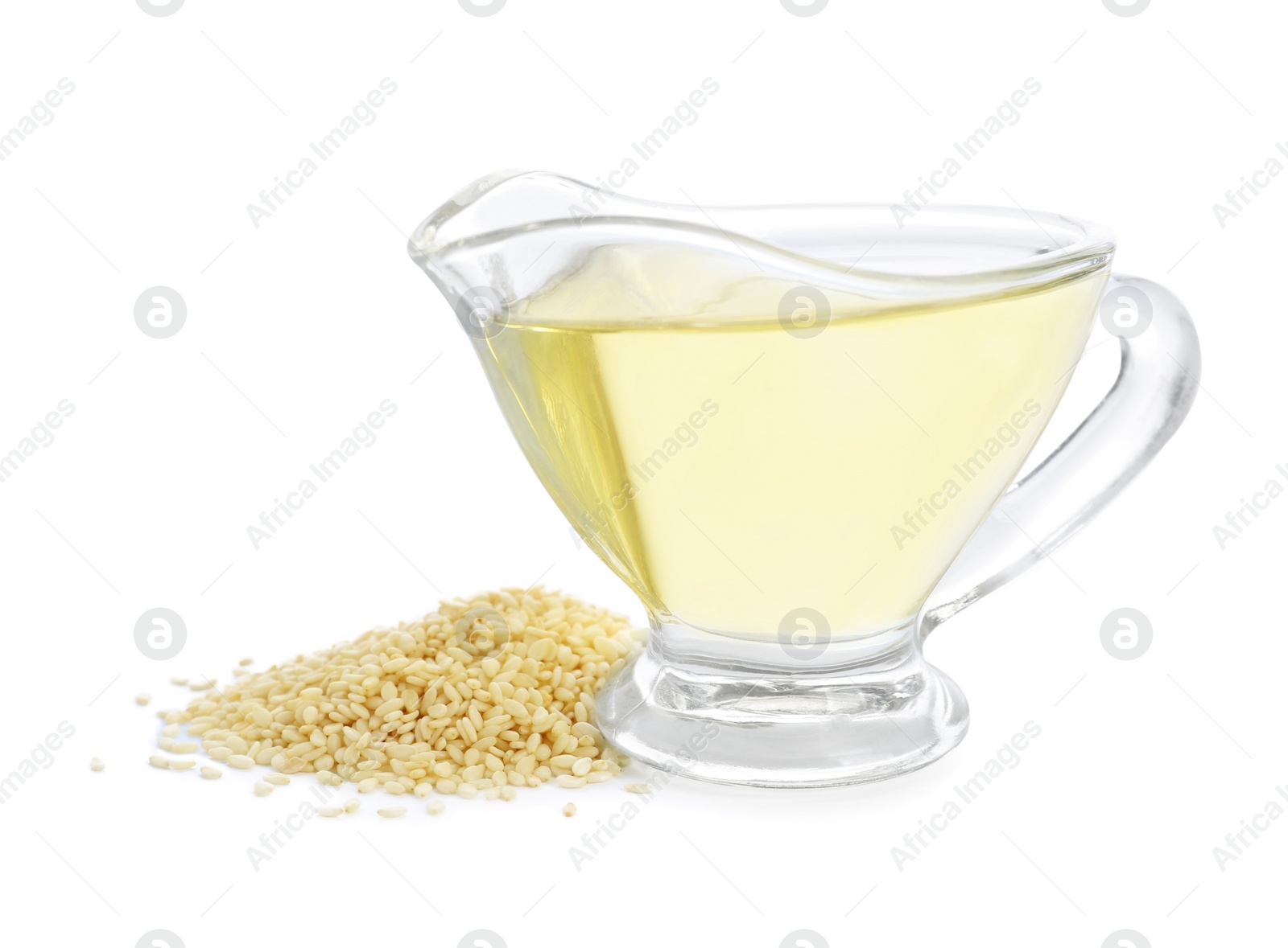 Photo of Glass sauceboat with fresh sesame oil and seeds isolated on white