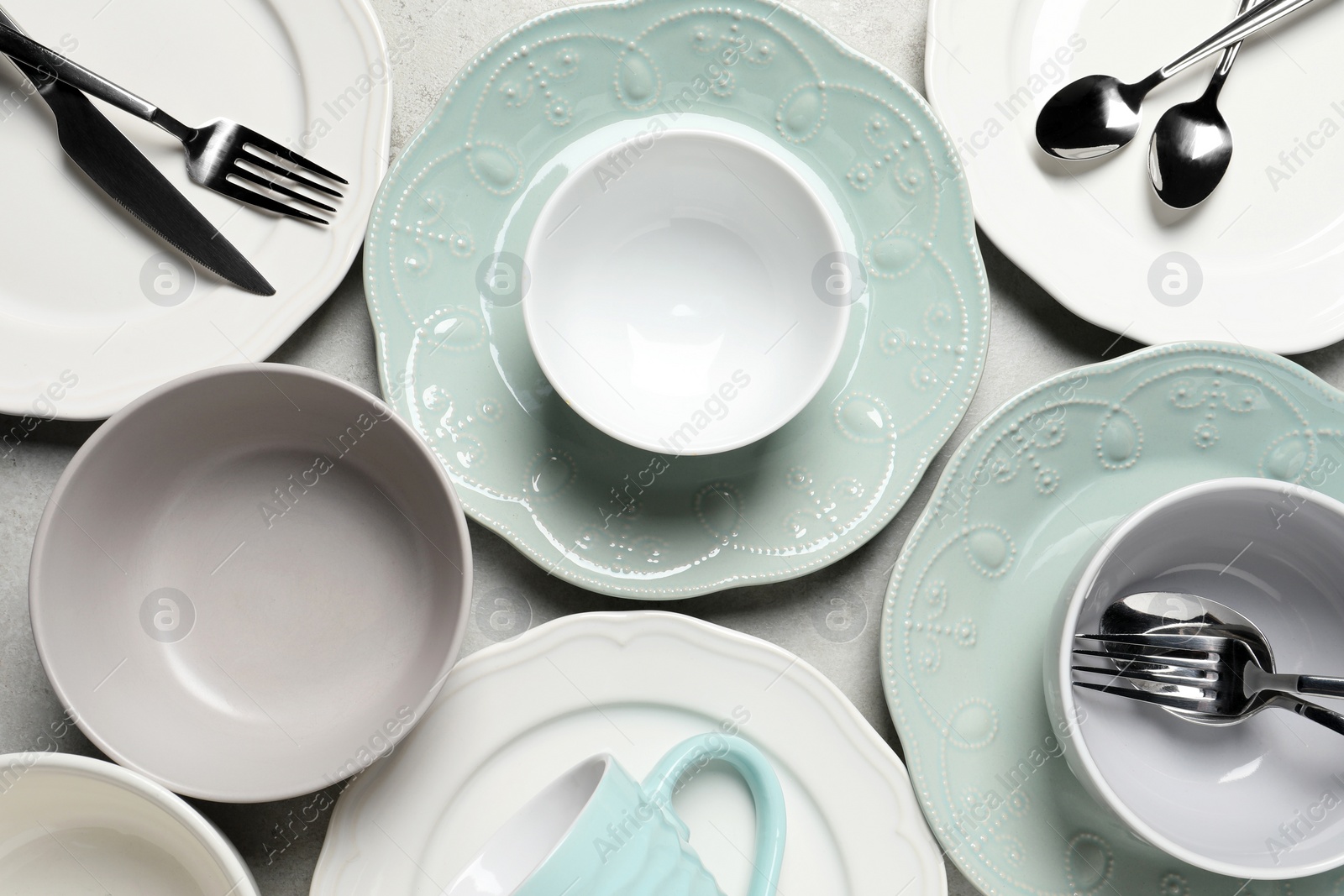 Photo of Beautiful ceramic dishware, cup and cutlery on light grey table, flat lay