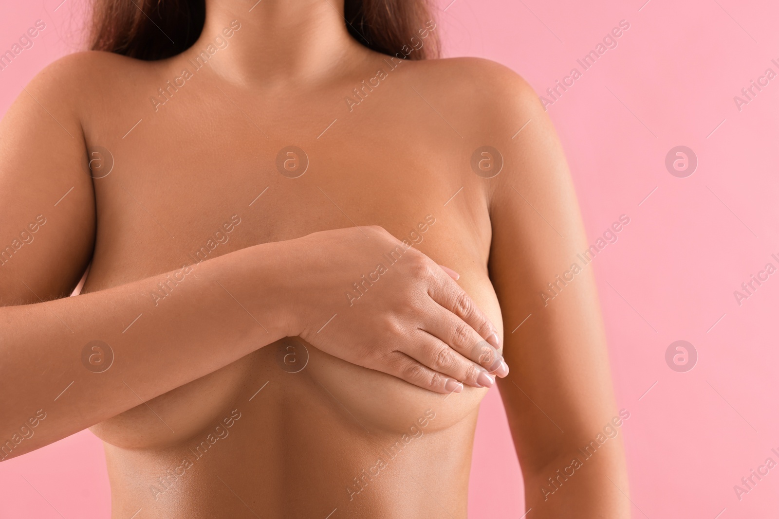 Photo of Naked woman covering her breast on pink background, closeup