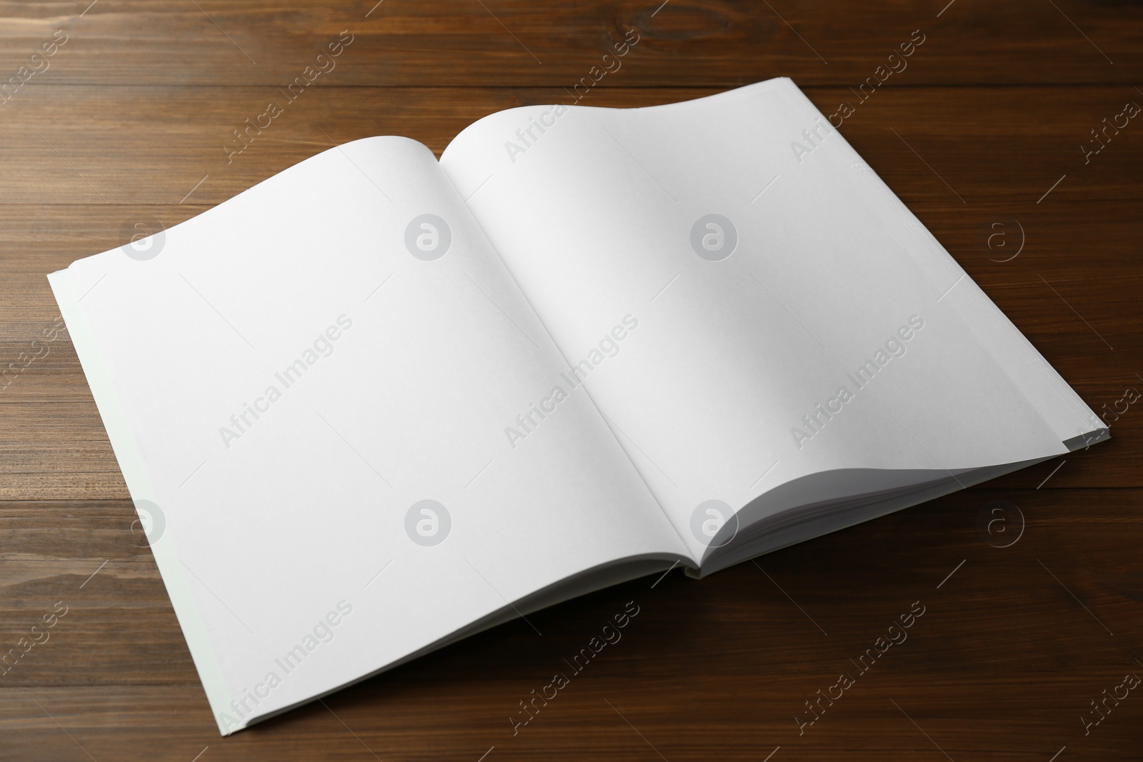 Photo of Open blank paper brochure on wooden table. Mockup for design