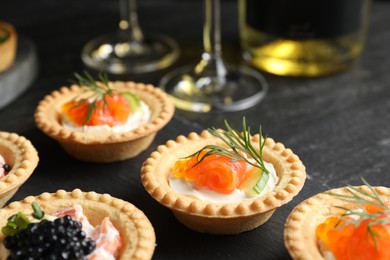 Photo of Delicious canapes with salmon and caviar on black table, closeup