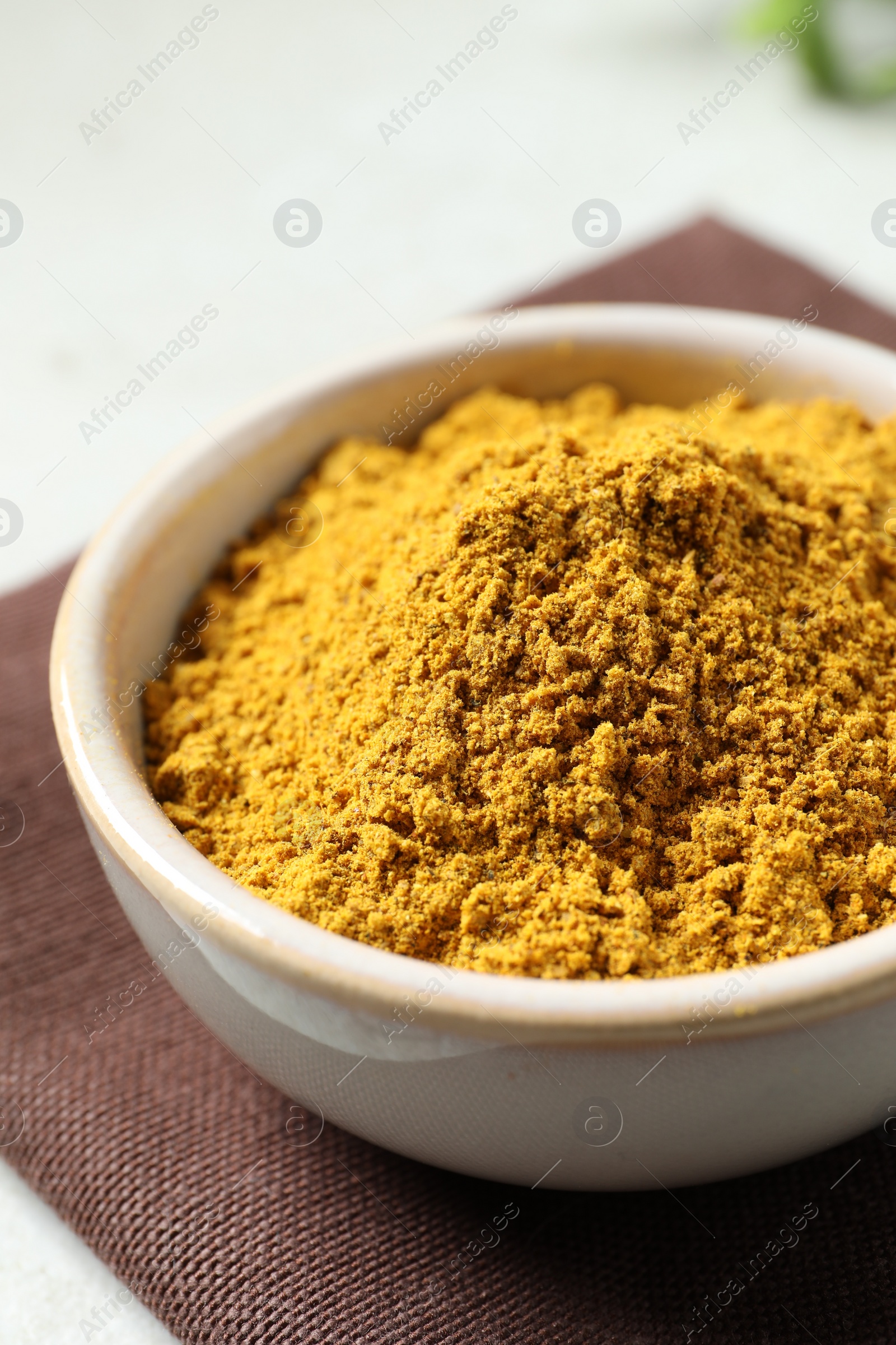 Photo of Curry powder in bowl on white table, closeup