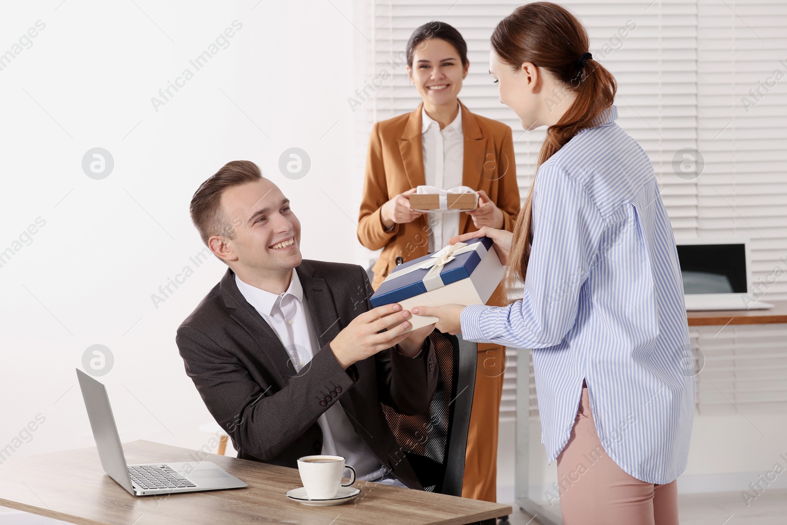 Photo of Woman presenting gift to her colleague in office