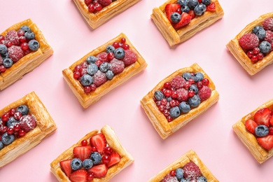 Photo of Fresh delicious puff pastry with sweet berries on pink background, flat lay