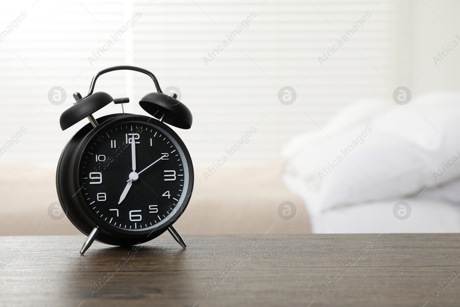 Photo of Black alarm clock on wooden table in bedroom, space for text