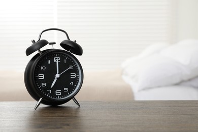 Photo of Black alarm clock on wooden table in bedroom, space for text