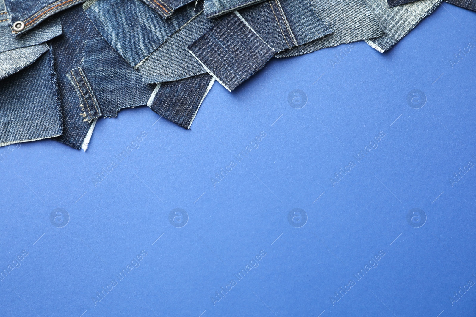 Photo of Flat lay composition with patches of old jeans on blue background. Space for text