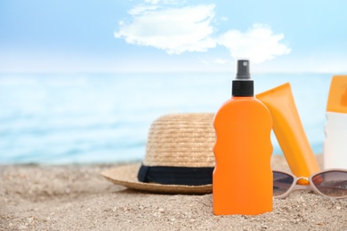 Photo of Composition with bottle of sun protection body cream on beach, space for design