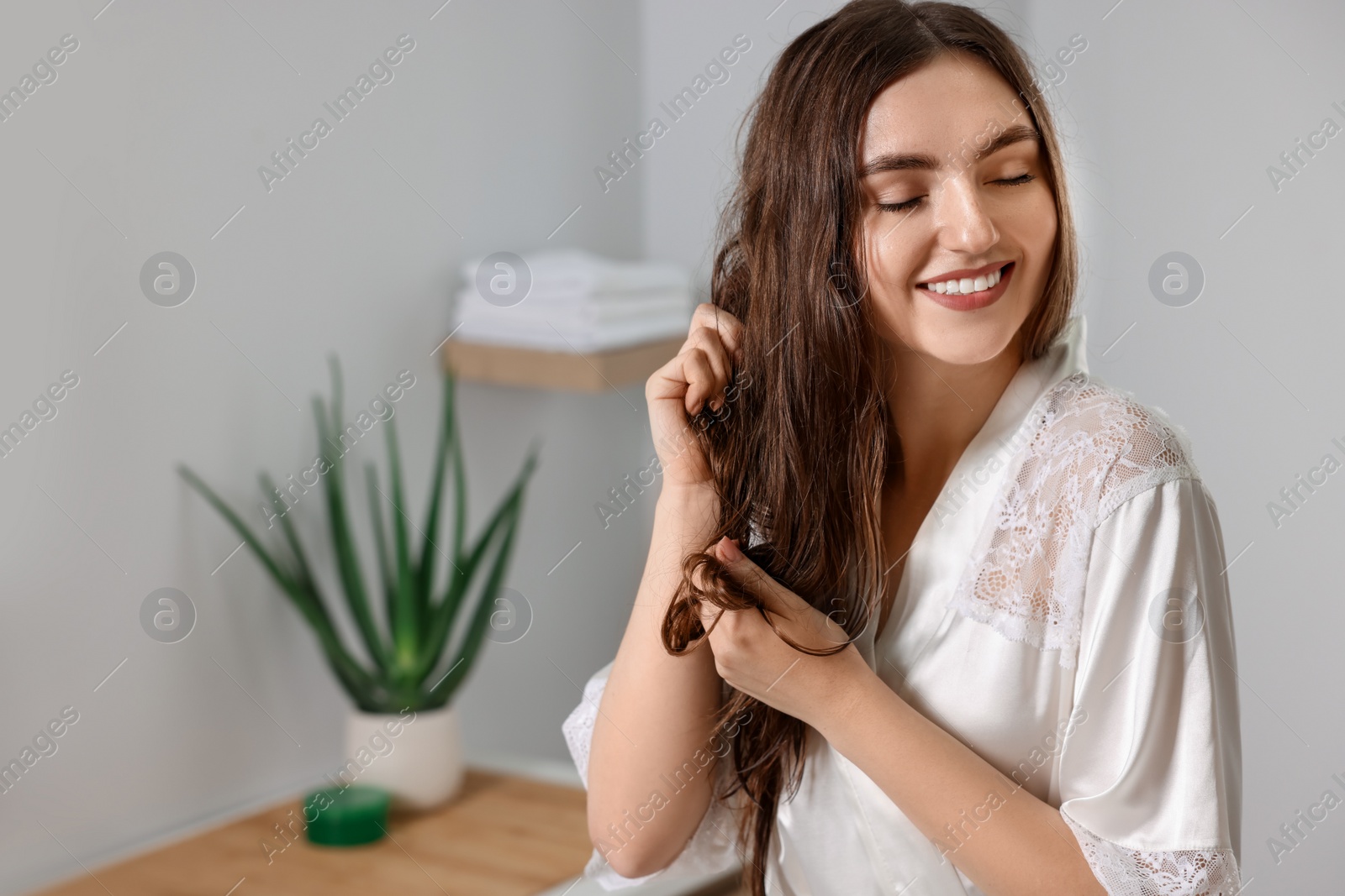 Photo of Young woman applying cosmetic hair mask in bathroom. Space for text