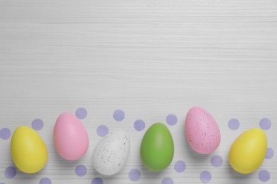 Photo of Flat lay composition with festively decorated Easter eggs on white wooden background. Space for text