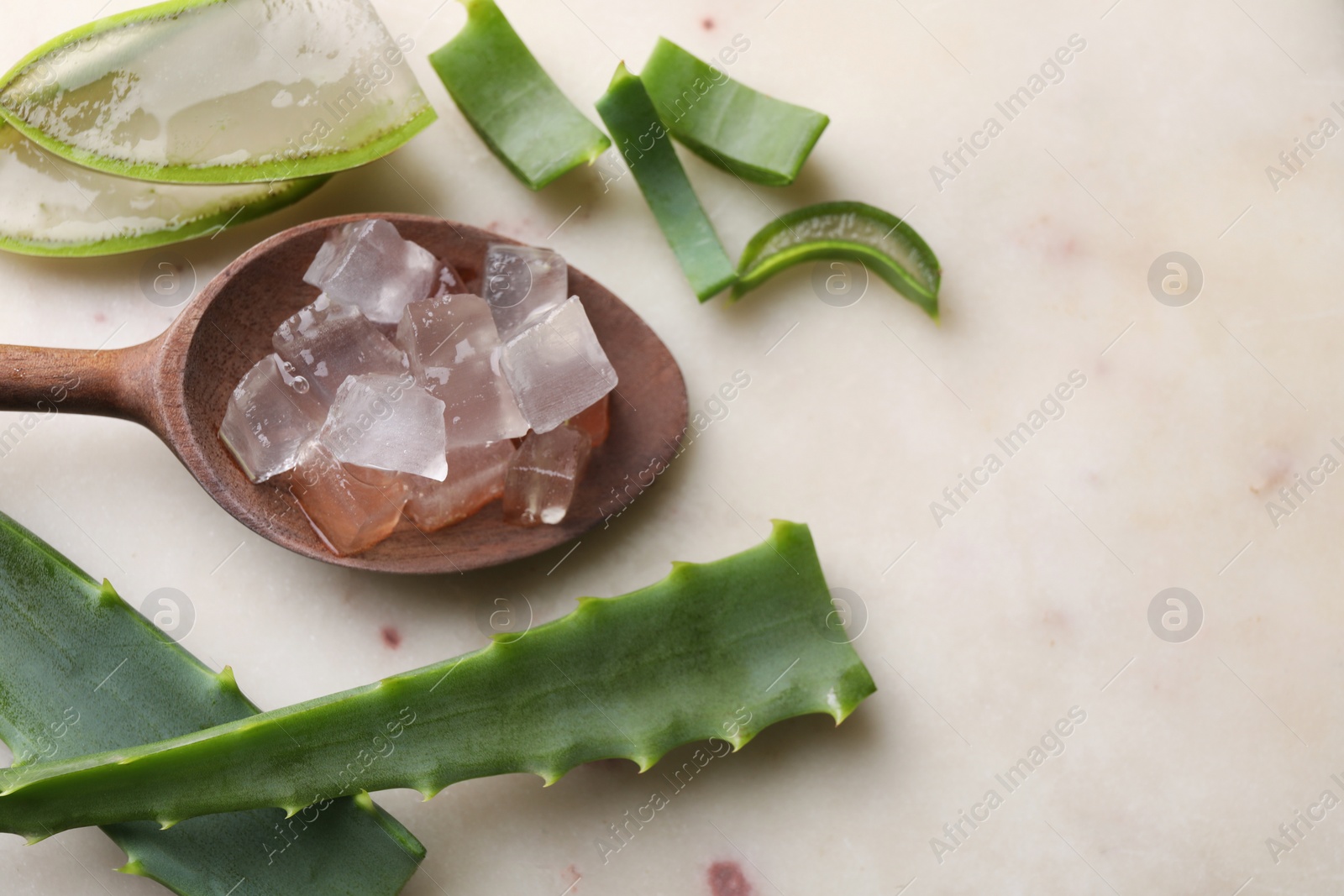 Photo of Aloe vera gel and slices of plant on light table, flat lay. Space for text