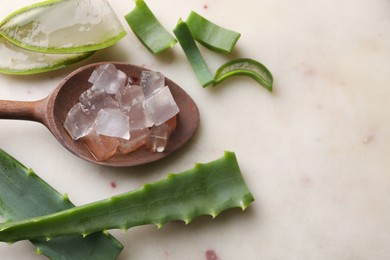 Aloe vera gel and slices of plant on light table, flat lay. Space for text