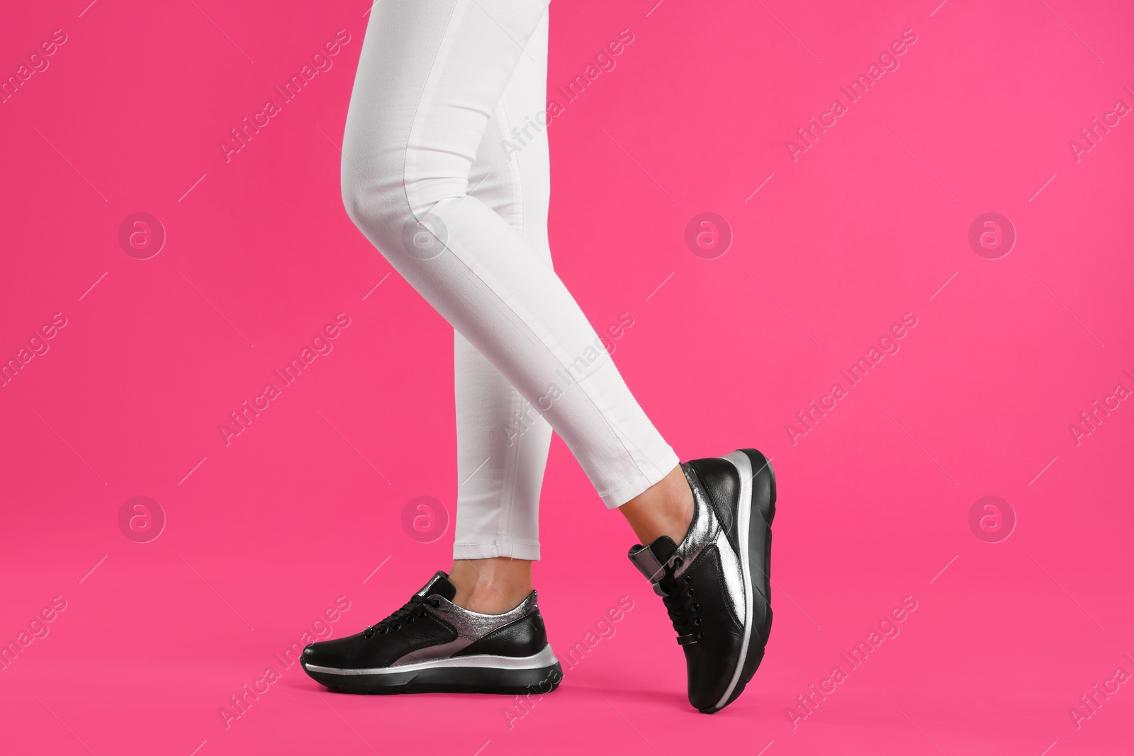 Photo of Woman wearing sneakers on pink background, closeup