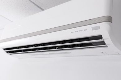 Photo of Modern air conditioner on white wall indoors, closeup view