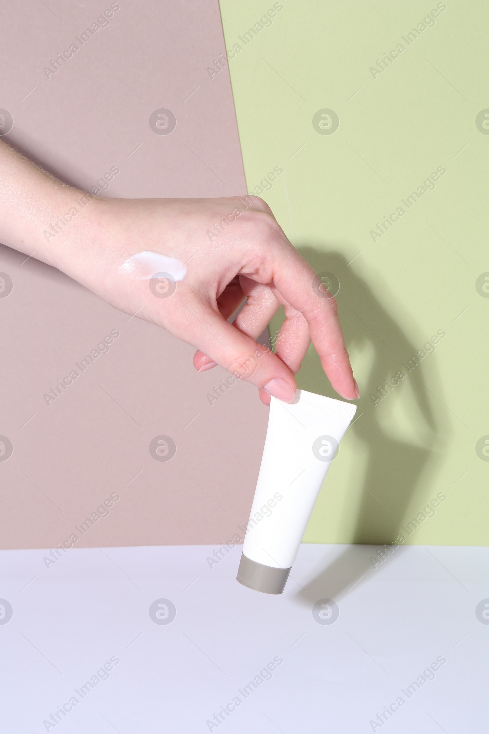 Photo of Woman with tube of cream on color background, closeup