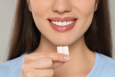 Woman with bubble gums on grey background, closeup