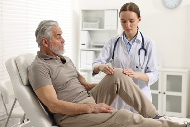 Arthritis symptoms. Doctor examining patient with knee pain in hospital