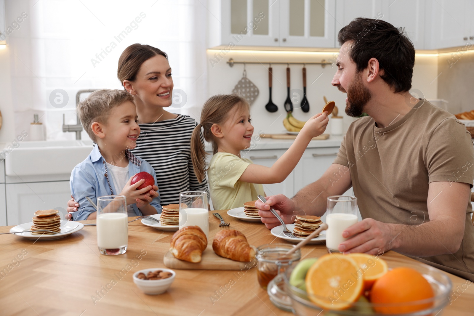 Photo of Happy family having fun during breakfast at table in kitchen