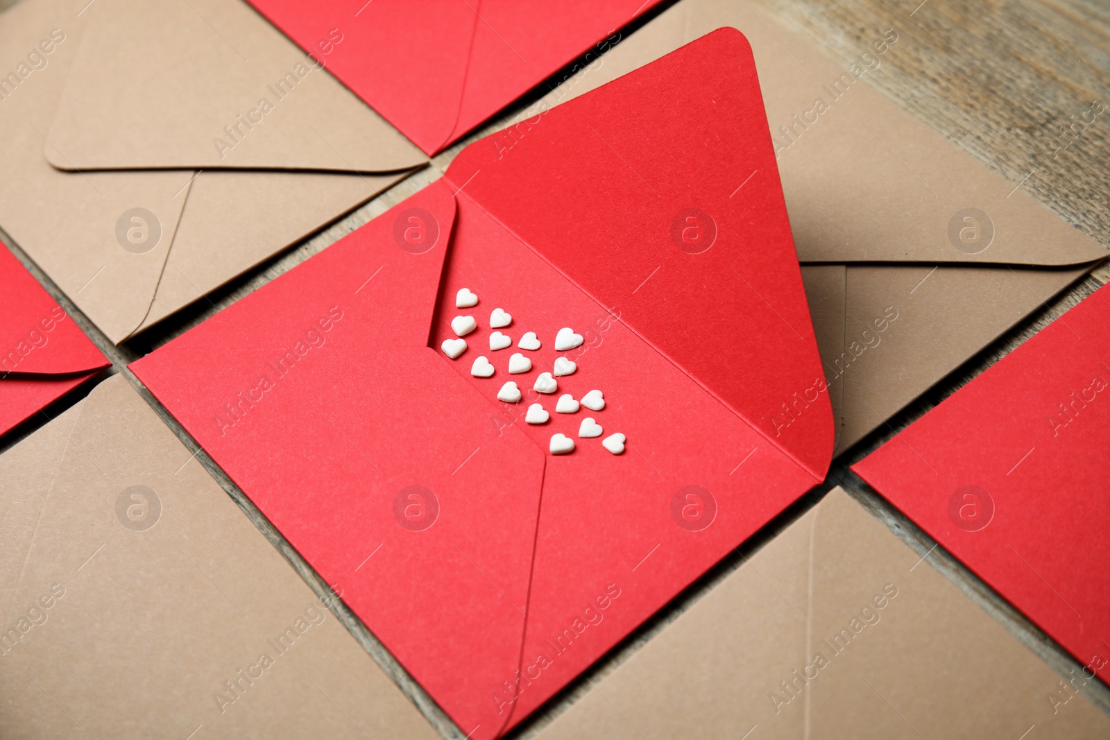 Photo of Envelopes and heart shaped sprinkles on wooden table, closeup. Love letters