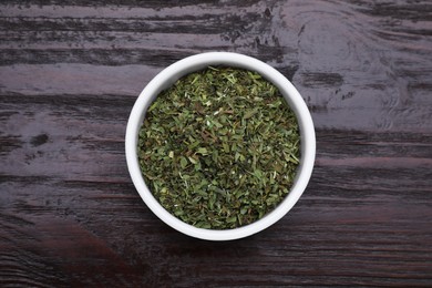 Photo of Dry tarragon in bowl on wooden table, top view