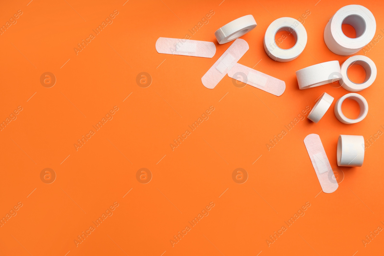 Photo of Different types of sticking plasters on orange background, flat lay. Space for text