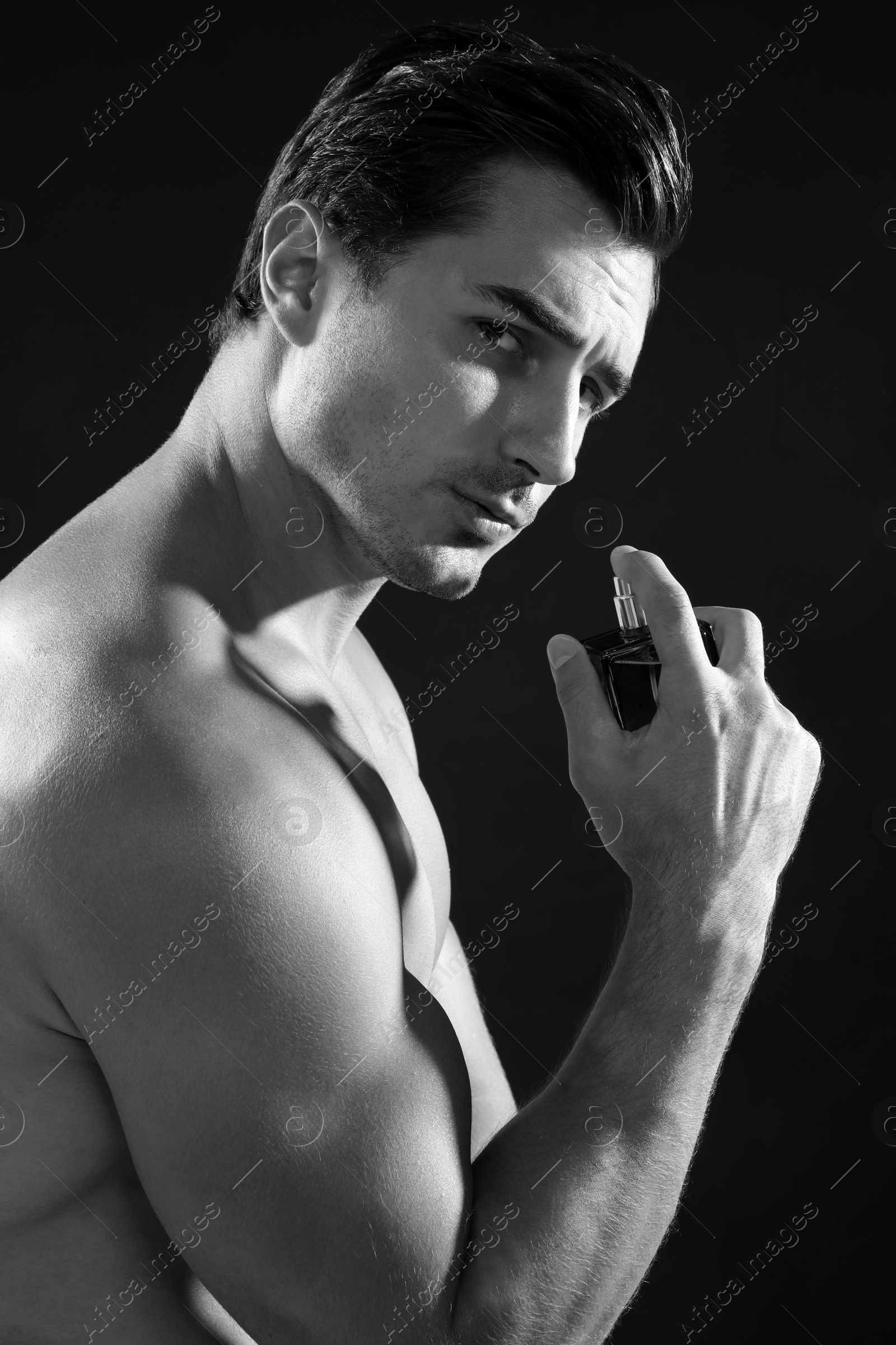 Photo of Handsome young man using perfume, black and white effect