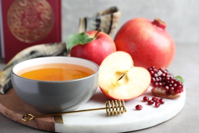 Photo of Honey, pomegranate, apples, shofar and Torah on grey table. Rosh Hashana holiday