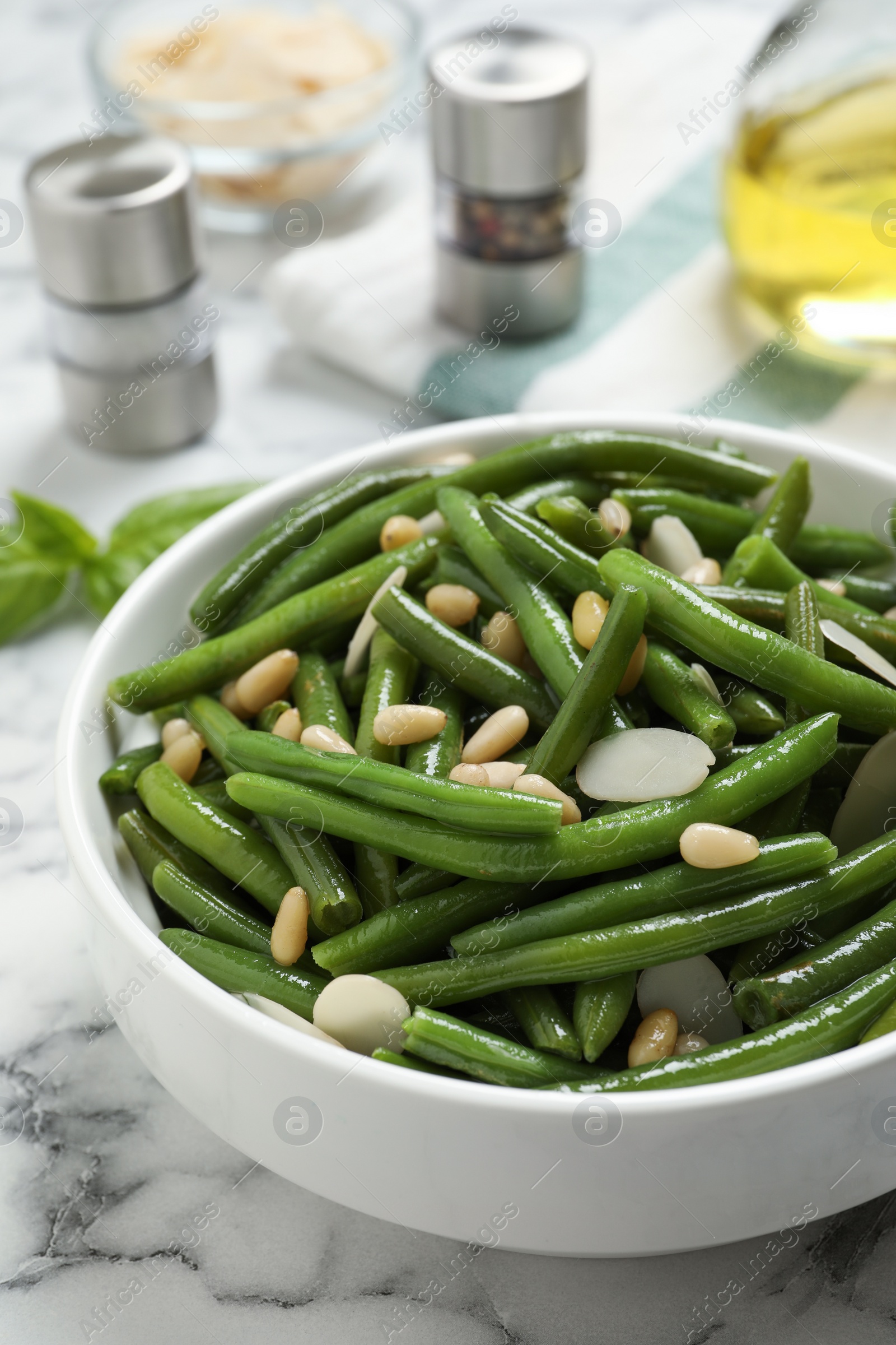 Photo of Bowl of tasty salad with green beans on white marble table