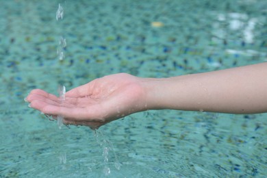 Photo of Water pouring into the girl's hand above pool, closeup