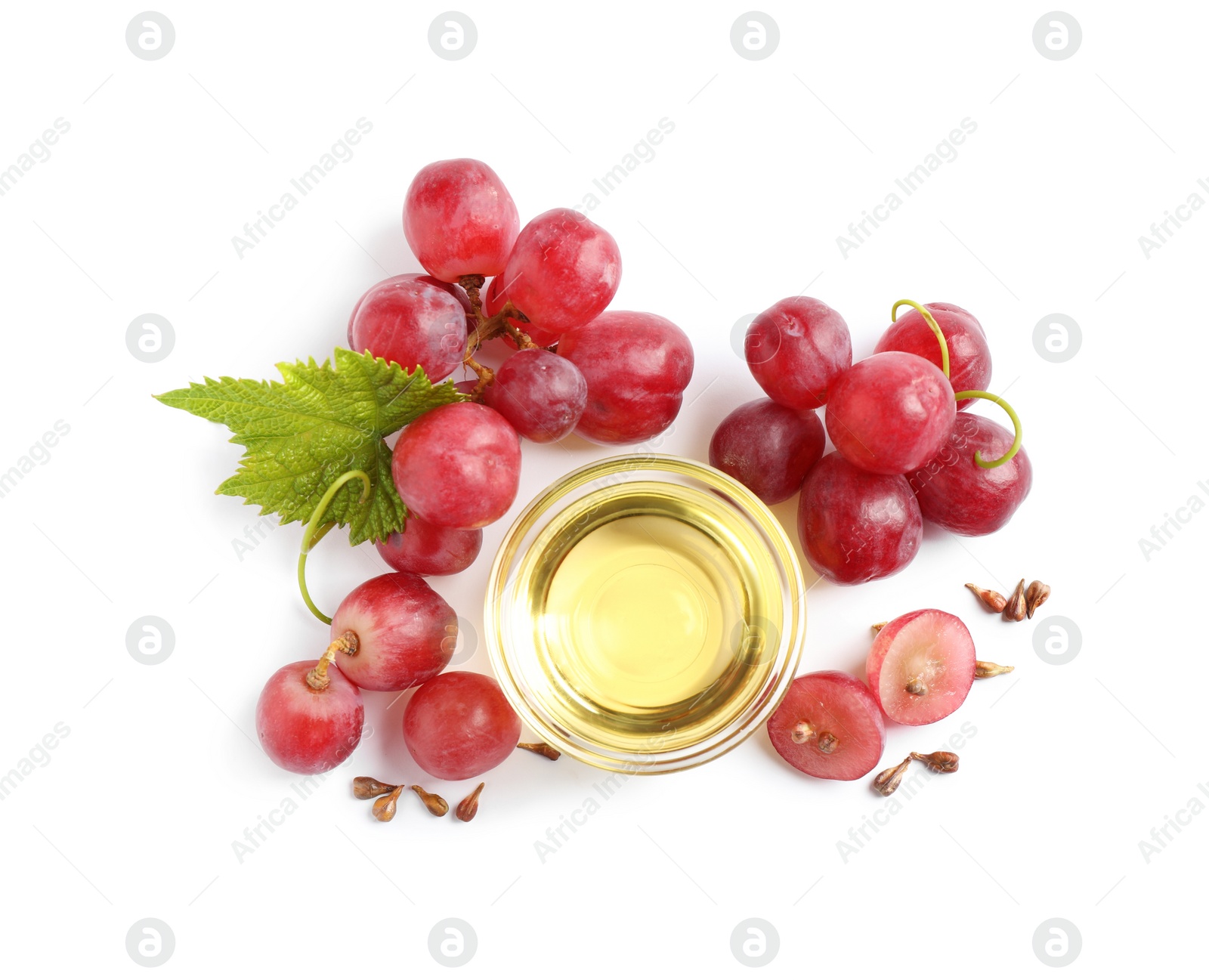 Photo of Organic red grapes, seeds and bowl of natural essential oil on white background, flat lay