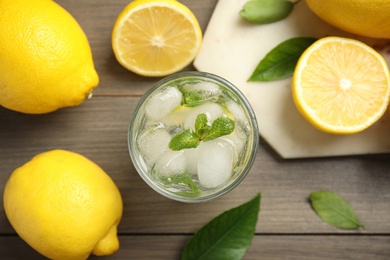 Cool freshly made lemonade and fruits on wooden table, flat lay