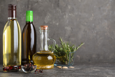 Composition with different sorts of cooking oil on grey table. Space for text